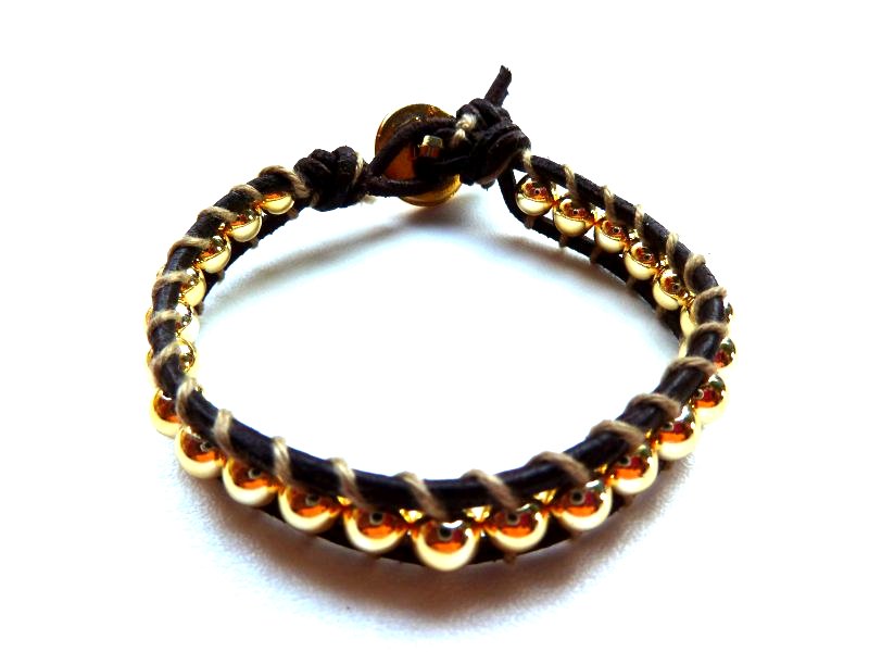 Chan Luu : cuoio nero, filo di cotone, perline dorate, bottone  in metallo